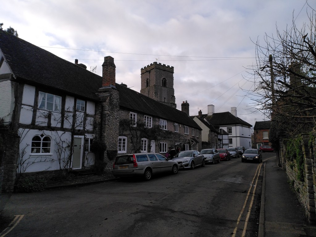 The old cottages of the Bull Ring, Much Wenlock, with the parish church tower behind them.